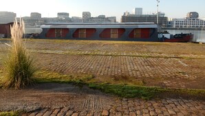 Un grand bâtiment industriel doté d’un toit plat, de nombreuses fenêtres et d’une façade rouge et grise.