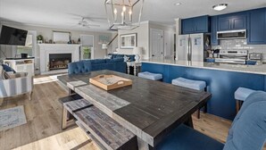 Une cuisine moderne avec des meubles de couleur bleue, une table à manger en bois et un four encastré.