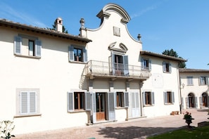 Un edificio con un balcone, diverse finestre e un vialetto in mattoni.