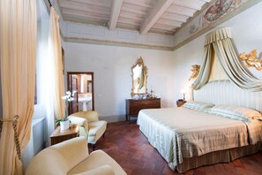 Un dormitorio con cama, una silla, cómoda, espejo y ventana con cortinas.