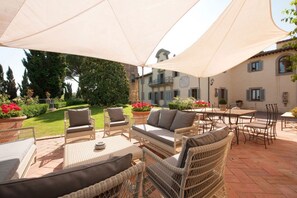 Un patio al aire libre con mobiliario de mimbre, una mesa y un paraguas grande.