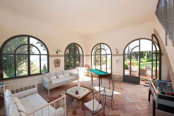 A spacious room with a pool table, foosball table, and a sofa.