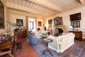 A traditional living room with a fireplace, sofas, a coffee table, and a patterned rug.