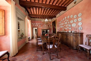 Una sala da pranzo con un tavolo e sedie in legno, un lampadario e una parete decorata con piatti.