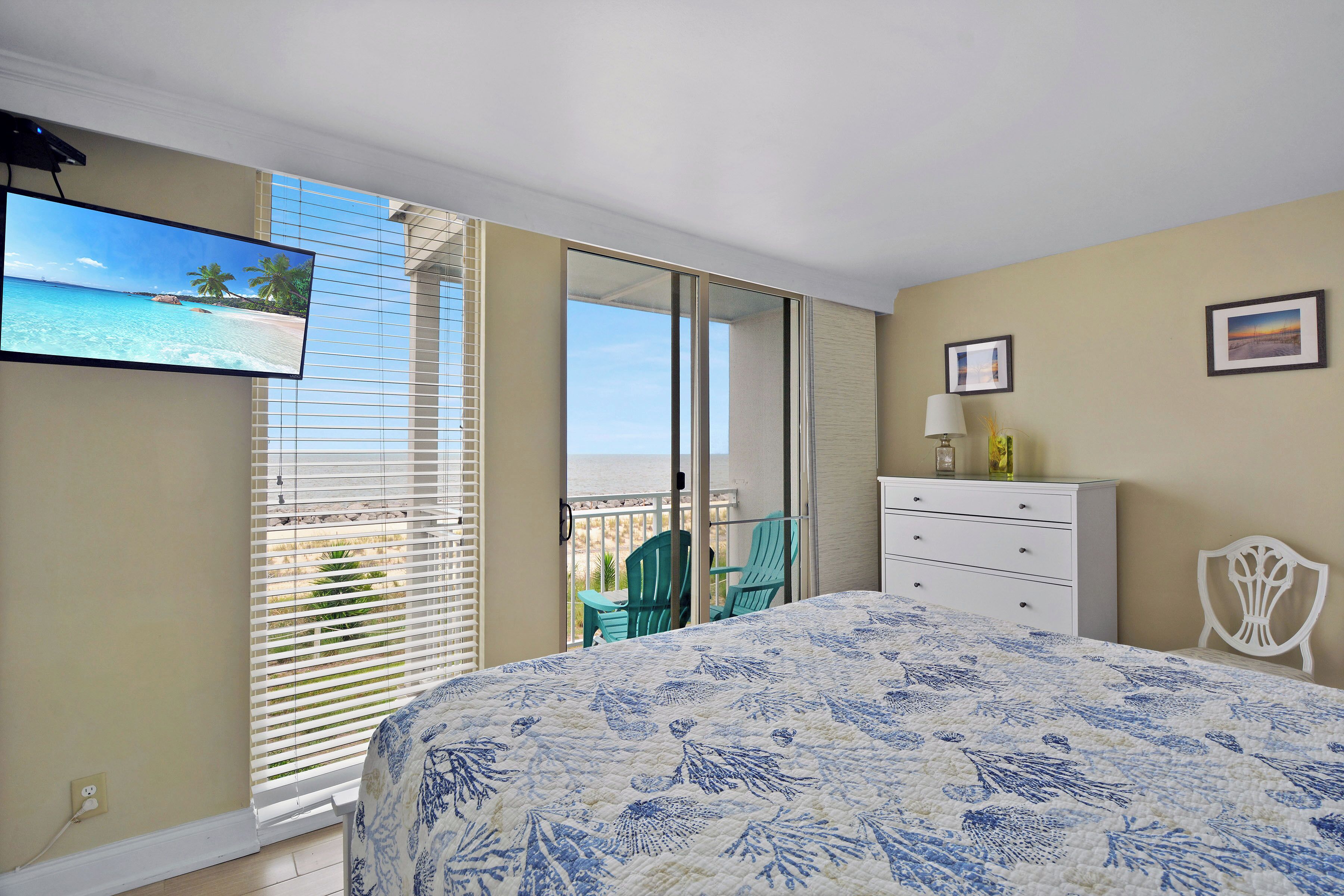 Un dormitorio con cama, televisor, cómoda y una silla.