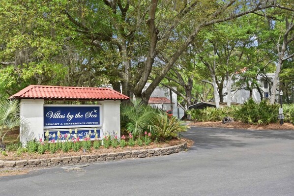 A sign for Villas by the Sea, a resort and conference center with a red-tiled roof and a landscaped garden.