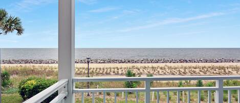 A balcony with a view of the beach and ocean.