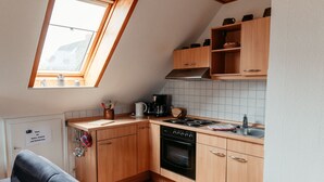 Una cocina compacta con armarios de madera, horno empotrado y una ventana sobre el fregadero.