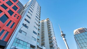A modern high-rise building with multiple balconies and a prominent tower in the background. - 3 Bedroom Home in City Central + FREE PARKING (Auckland CBD)