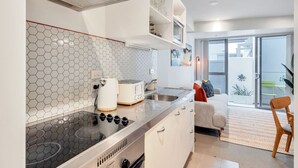 A modern kitchen with a hexagonal tile backsplash, a built-in stove, and a dining area with a sofa and a chair. - 3 Bedroom Home in City Central + FREE PARKING (Auckland CBD)