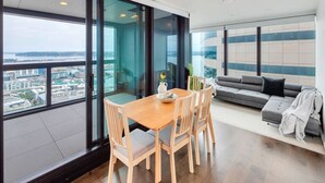 Una sala de estar moderna con comedor, ventanas grandes y vistas a la ciudad.
