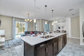 A modern kitchen with a large island, dark cabinetry, and pendant lighting.