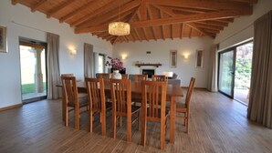 Un vaste espace dédié à la salle à manger, avec des chaises et une table en bois, un plafond en bois et une grande fenêtre agrémentée de rideaux.