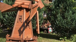 Uma construção de moinho de vento de madeira com uma placa que diz "Rügenland" em um jardim.