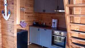 Uma cabana de madeira compacta com cozinha compacta, incluindo geladeira, fogão e pia.