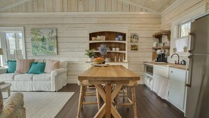 Un salon chaleureux avec une table à manger en bois, un canapé blanc agrémenté de coussins turquoise et un grand tableau accroché au mur.