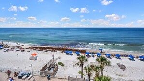 Une plage avec des parasols, une tour de surveillance pour les sauveteurs et une vue dégagée sur l’océan.