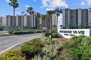 Señal de los apartamentos Phoenix VI-VII con vista a edificios residenciales altos y palmeras.