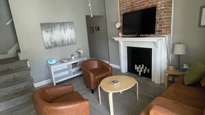 Ein Wohnzimmer mit Kamin, Fernseher und Deckenventilator.