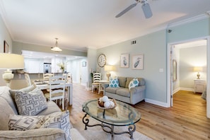 Relax in this inviting living room with a comfortable sofa, dining area, and ceiling fan.