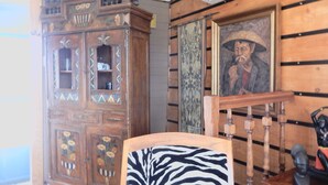 A room with a wooden cabinet, a framed painting, and a zebra-patterned chair. - Appartement "voyage Autour du Monde" (Bordeaux)