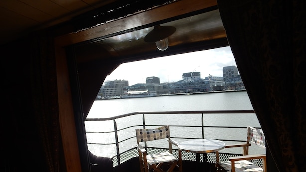 A deck with a table and chairs, overlooking a body of water with buildings in the background. - Appartement "voyage Autour du Monde" (Bordeaux)