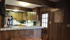 Una cocina con armarios de madera, una encimera, una licuadora, un microondas y una cafetera.