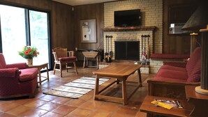 Un salón acogedor con chimenea, muebles de madera y un televisor montado en la pared.