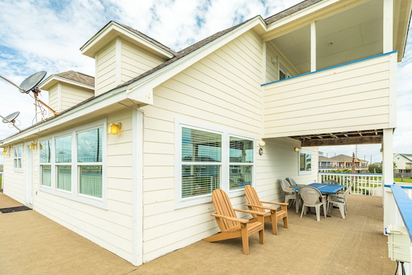A two-story house with a covered patio area featuring outdoor furniture and a table.