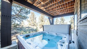 A hot tub under a wooden pergola with a view of trees. - Juniper Ranch - Golf Cart Included | Sleeps 10 (Powell Butte)