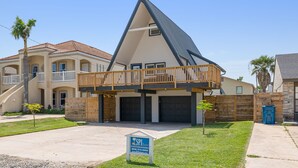 A modern two-story house with a balcony, a garage, and a well-maintained lawn.