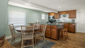 A kitchen with wooden cabinets, a dining table with chairs, and a microwave.