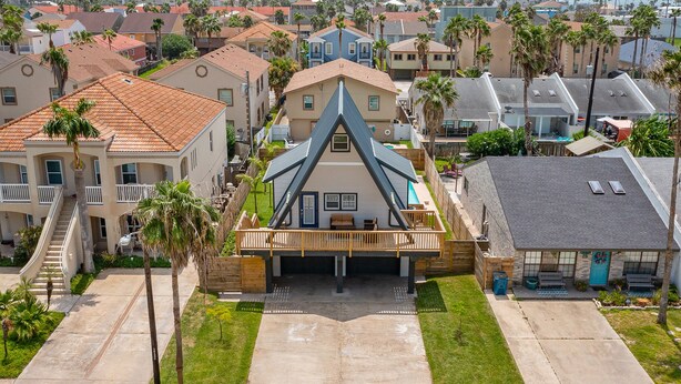 A residential area with a central house featuring a unique triangular roof, a covered porch, and a small front yard.