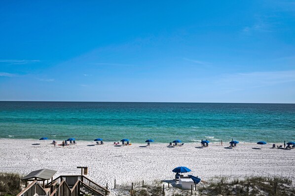 Guests can enjoy a relaxing beach experience with lounge chairs and umbrellas on the sandy beach.