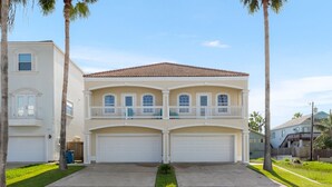A two-story house with a balcony, a garage, and a well-maintained lawn.