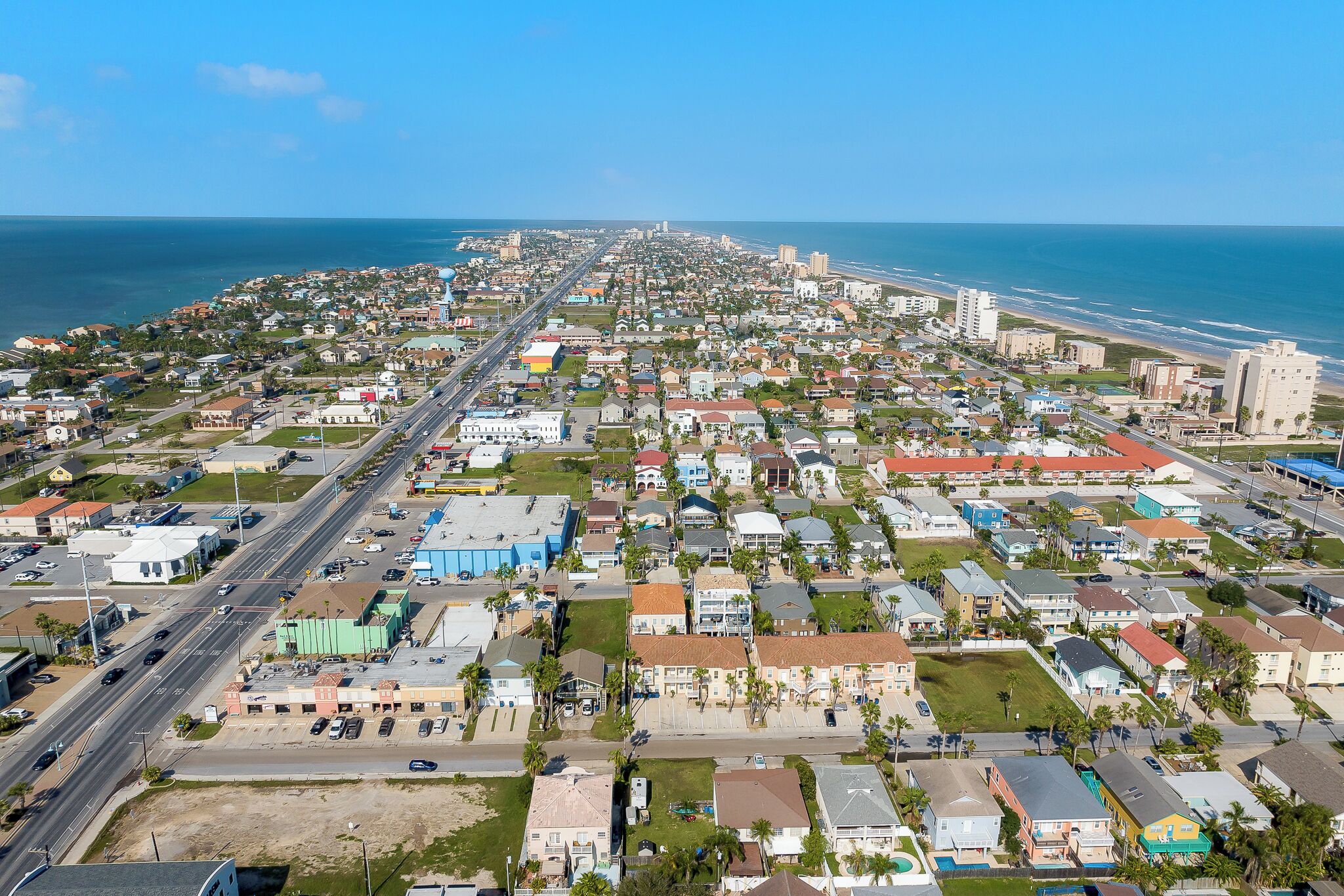 Vista aérea de una ciudad costera con una avenida amplia, zonas residenciales y una playa.