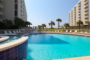 Relax by the resort pool surrounded by palm trees and lounge chairs.