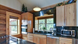 A modern kitchen with wooden cabinets, a granite countertop, stainless steel appliances, and a window providing natural light. - Creekside Log Cabin- conveniently located and direct creek access  (Buena Vista)