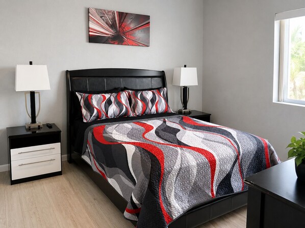 A modern bedroom with a black headboard, two bedside tables with lamps, a large abstract painting on the wall, and a window with a view of greenery. - RIVERFRONT RUBY RED HOME & SPA & PRIVATE DOCK & INLET FUN! (Bullhead City)