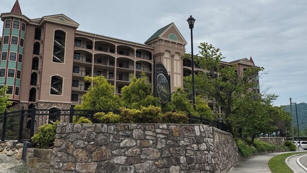 A multi-story hotel with a stone facade, balconies, and a sign indicating it is a Sheraton hotel. - Convenient Creekside condo with large wrap around balcony, close to everything! (Gatlinburg)