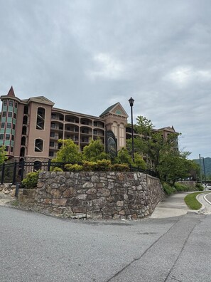A multi-story hotel with a stone facade, balconies, and a sign indicating it is a Sheraton hotel. - Convenient Creekside condo with large wrap around balcony, close to everything! (Gatlinburg)