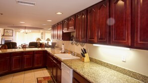 A kitchen with dark wooden cabinets, granite countertops, a dishwasher, and a sink. - Convenient Creekside condo with large wrap around balcony, close to everything! (Gatlinburg)
