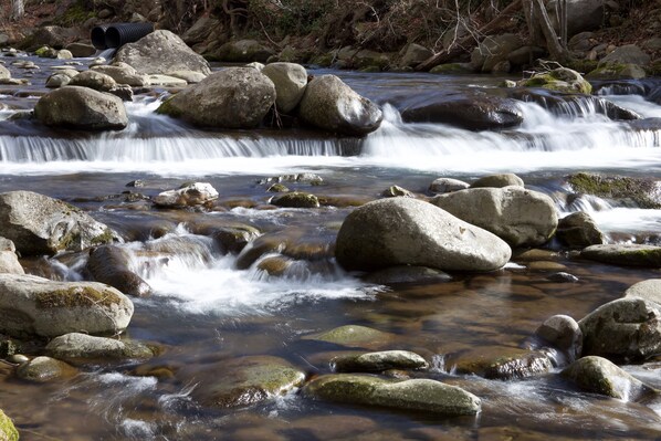 A stream flowing over rocks with a clear water surface. - Convenient Creekside condo with large wrap around balcony, close to everything! (Gatlinburg)