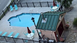 A rooftop pool with lounge chairs, a small building, and a street view. - Convenient Creekside condo with large wrap around balcony, close to everything! (Gatlinburg)