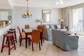 Relax in this spacious living area with a dining setup, featuring a sofa, armchair, and glass-top table.