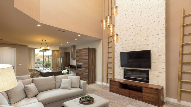 A modern living room with a beige sofa, a coffee table, and a flat-screen TV mounted on a brick-patterned wall. - Spectacular 4BR/4.5Bath Home/Near Disney/Wi-Fi/ Parking/BBQ/Heated Pool Shared (Celebration)