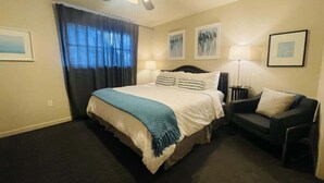 Een hotelkamer met een bed, een stoel, een plafondventilator en kunstwerken aan de wanden.
