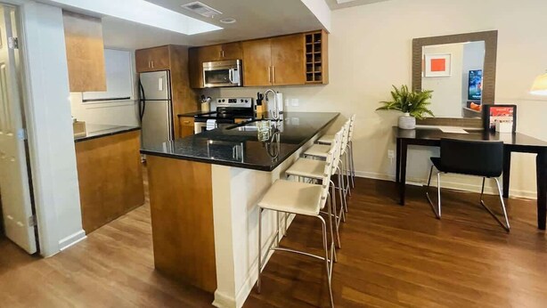 Een moderne keuken met een centraal eiland, roestvrijstalen apparatuur en een eethoek met barkrukken.