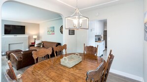 A dining area with a round wooden table, six chairs, a woven basket, and a modern chandelier.