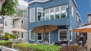 A two-story building with a balcony, outdoor seating with umbrellas, and a small shop.